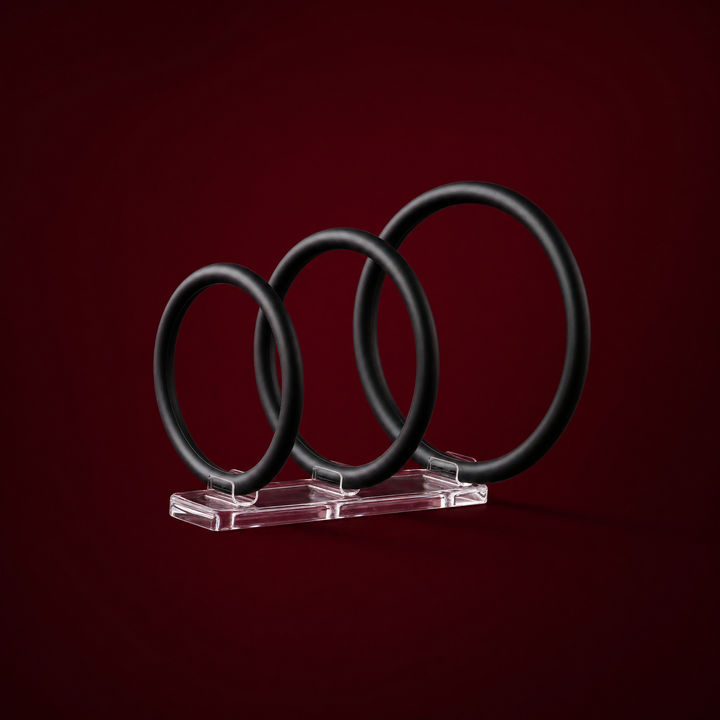 Esme three-pack of black silicone rings on a burgundy studio background