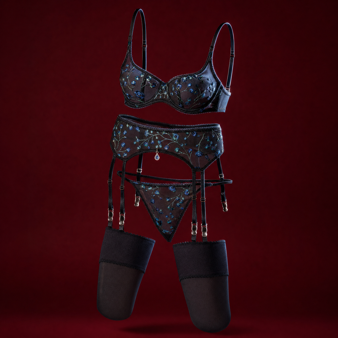 Emmanuelle black sheer mesh lingerie set embroidered with blue flowers, with bra, garter belt, thong and stockings, on a deep burgundy background