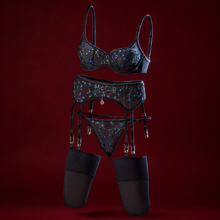 Emmanuelle black sheer mesh lingerie set embroidered with blue flowers, with bra, garter belt, thong and stockings, on a deep burgundy background