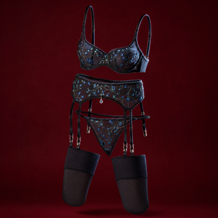 Emmanuelle black sheer mesh lingerie set embroidered with blue flowers, with bra, garter belt, thong and stockings, on a deep burgundy background