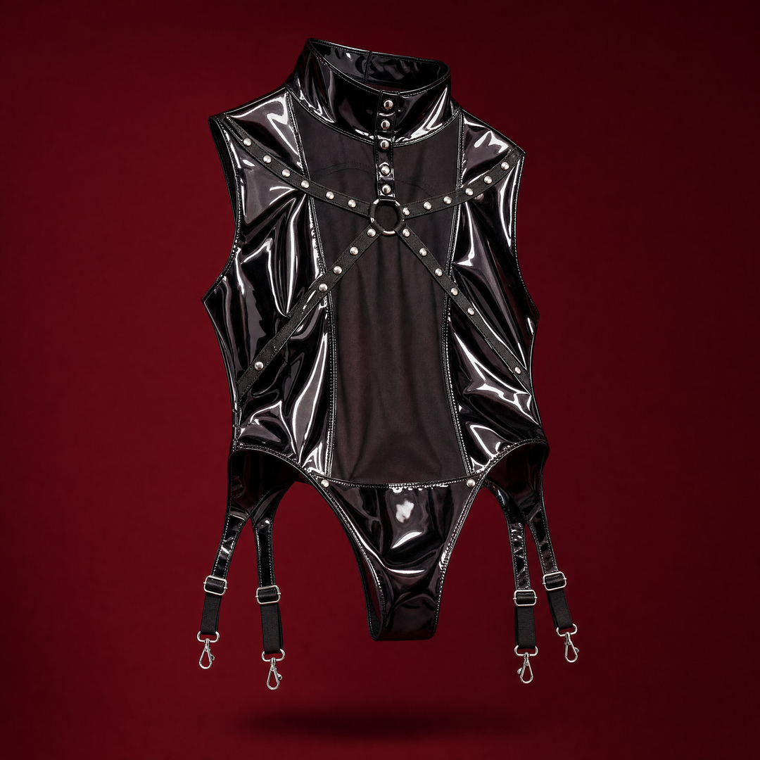 GLOSS PANEL | BODYSUIT - sleeveless panelled bodysuit in high-shine patent with studded mock collar, sheer black mesh centre front, studded strap harness with silver O-ring, teardrop hip cut-outs and four garter straps, on a deep burgundy studio background